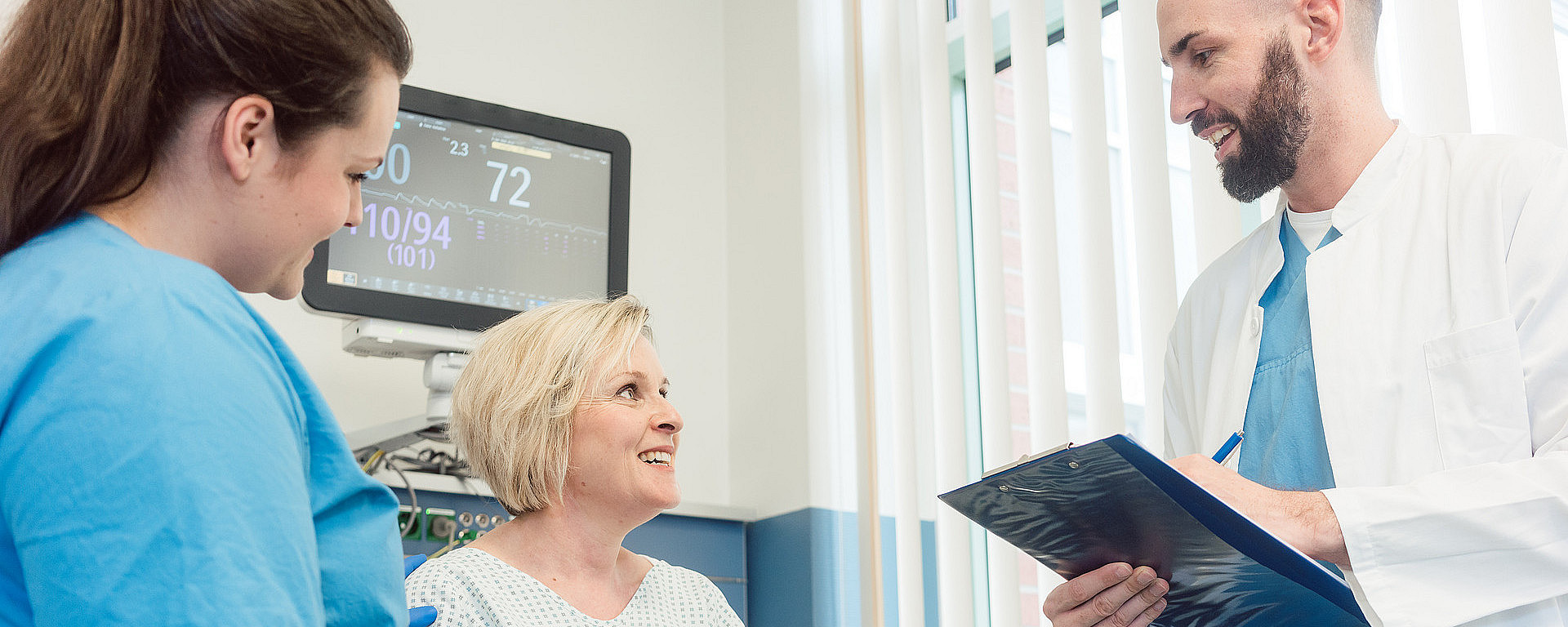 Arzt und Krankenschwester reden mit Patientin im Krankenbett