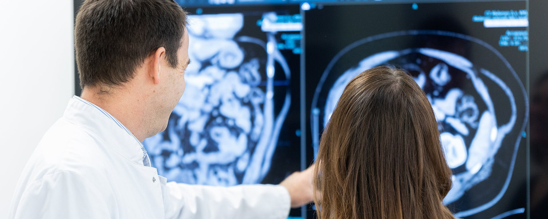 Ein Arzt schaut sich mit einer Patientin einen Scan auf einem Monitor an