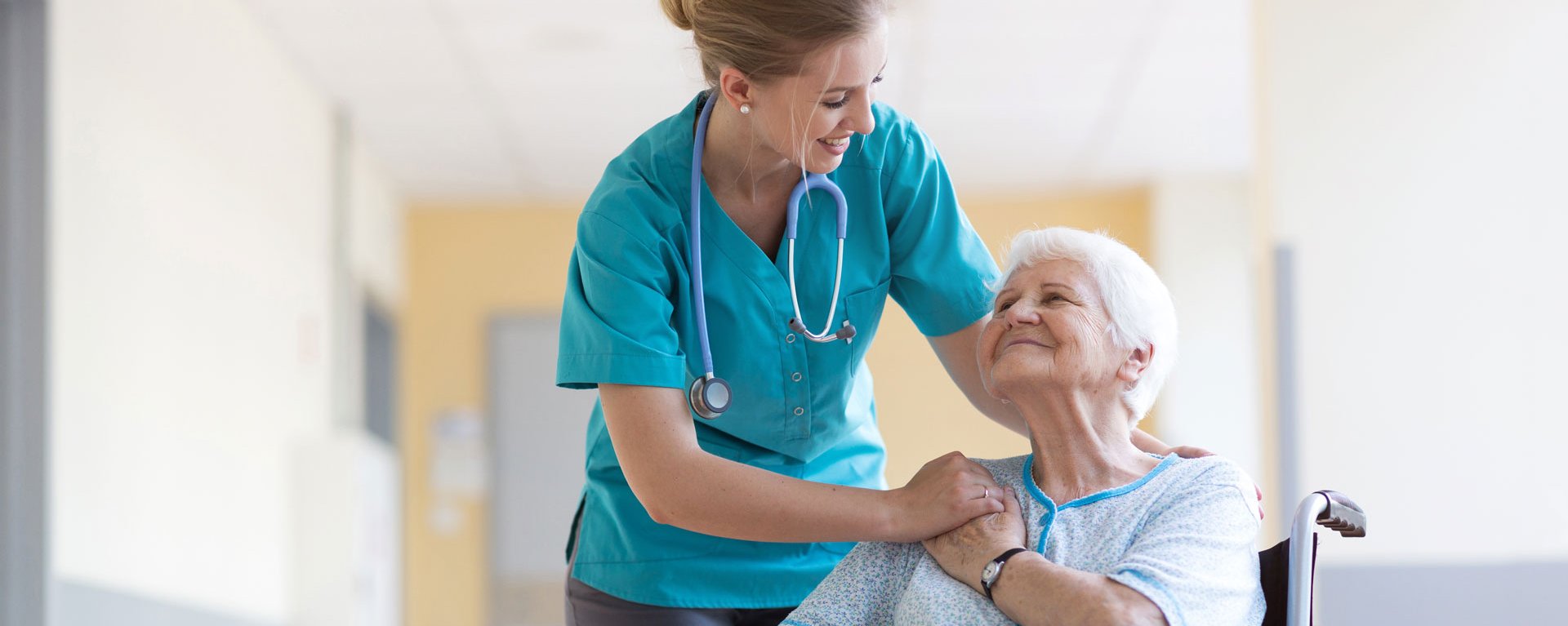 Eine Pflegerin der modernen Kurzzeitpflege im Klinikverbund Allgäu legt einen Arm um eine Seniorin und hält mit ihrer anderen Hand liebevoll die Hand der Frau