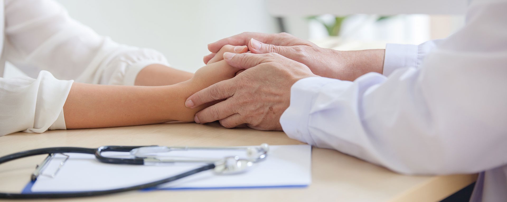 Eine Ärztin des Klinikverbunds Allgäu hält die Hände einer Patientin während einer Besprechung.