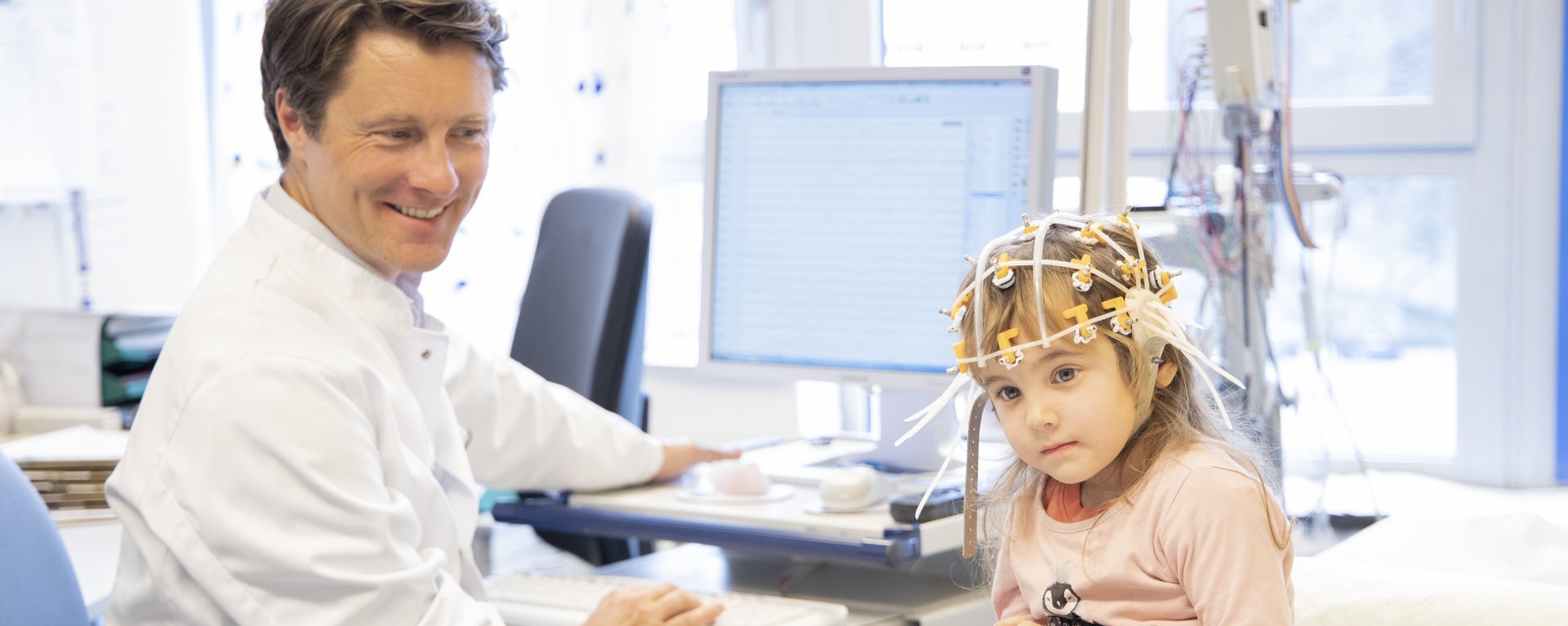 Kinderarzt untersucht ein Kind im behandlungszimmer und tippt etwas in seinen Coumputer