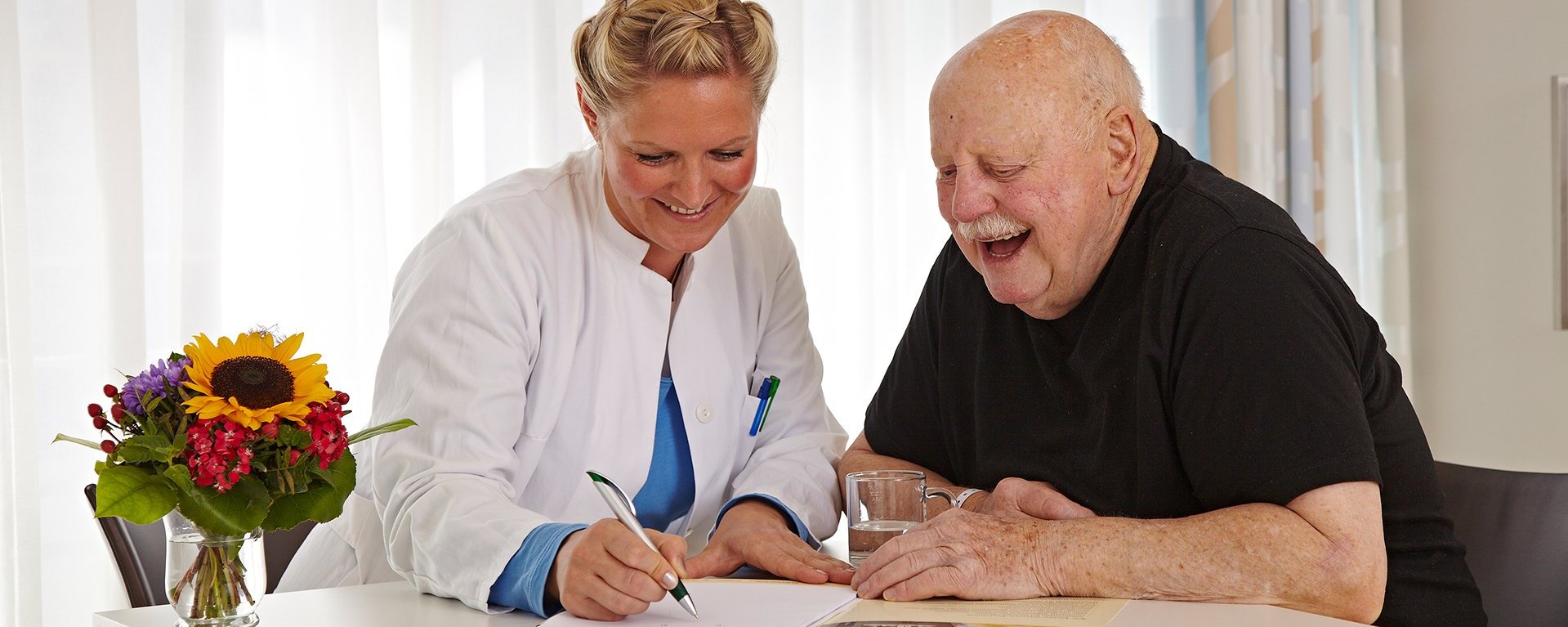 Altersmedizin im Klinikverbund Allgäu, Ärztin mit Patient an einem Tisch