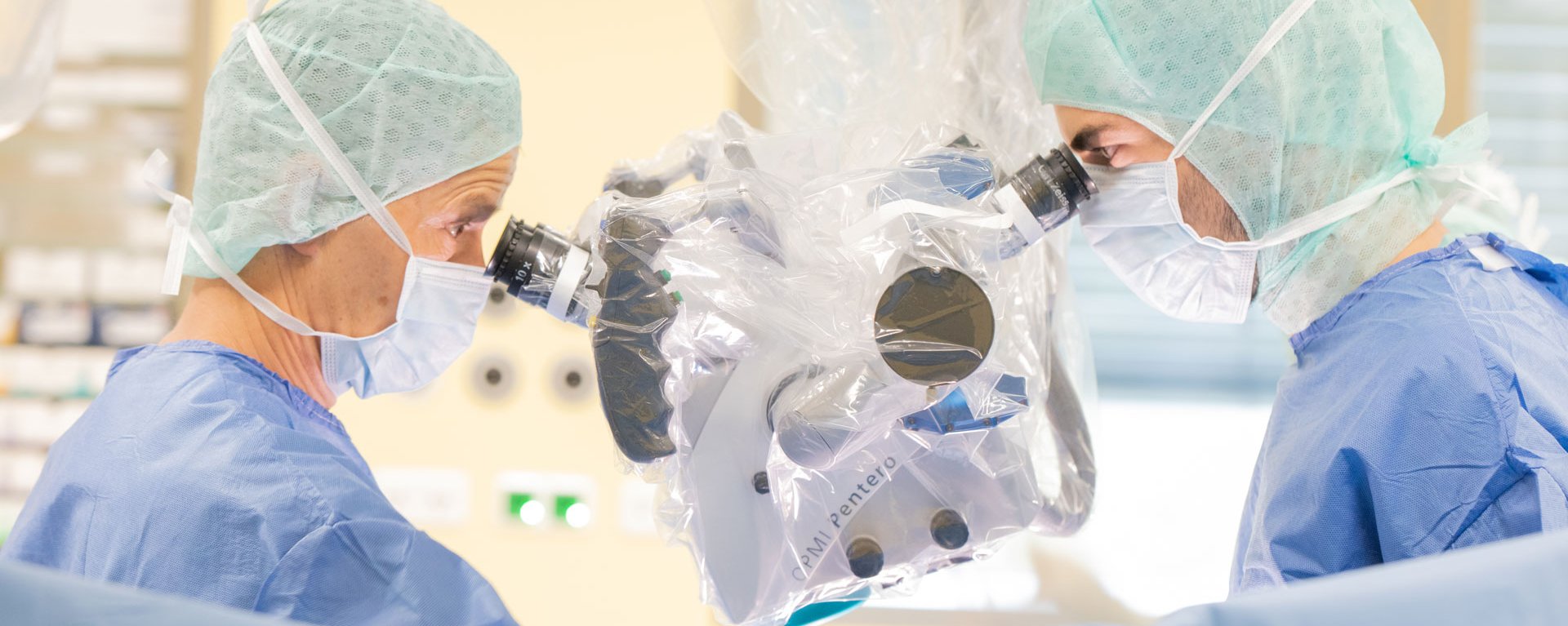 Zwei Neurochirurgen blicken während einer Operation in ein medizinsiches High Tech Gerät der Firma CPMI Pentero