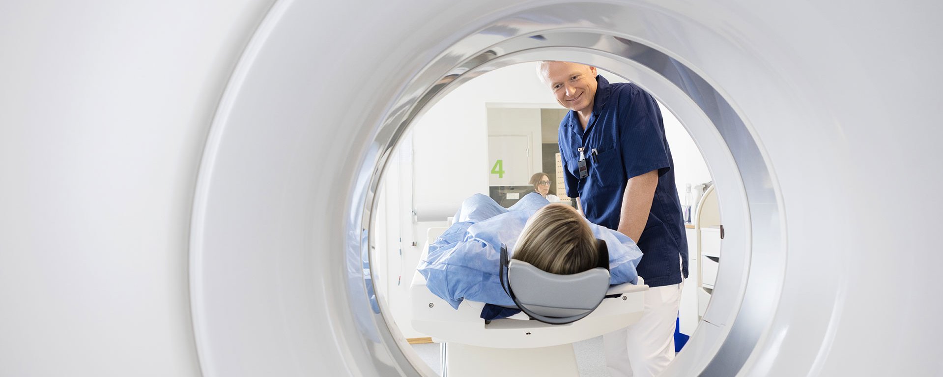 Männlicher Arzt des Klinikverbunds Allgäu betrachtet eine Patientin, die einen CT-Scan durchläuft.