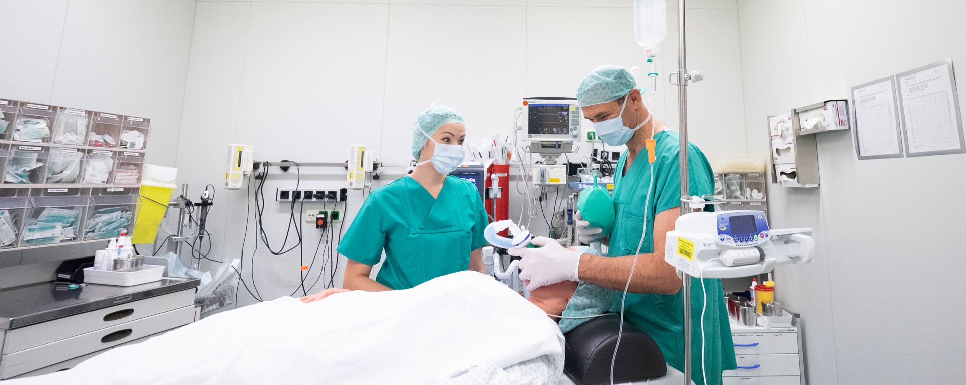 Ein Arzt und eine Ärztin der Anästhesiepflege an der Klinik Mindelheim beaufsichtigt die Beatmung einer Patientin - zu sehen ist der gesamte Raum