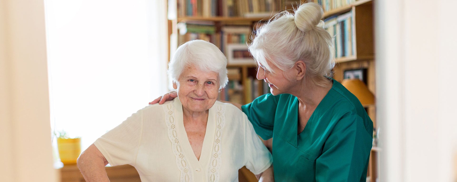 Pflegehelferin des Klinikverbunds Allgäu hilft einer ältere Frau beim gehen.