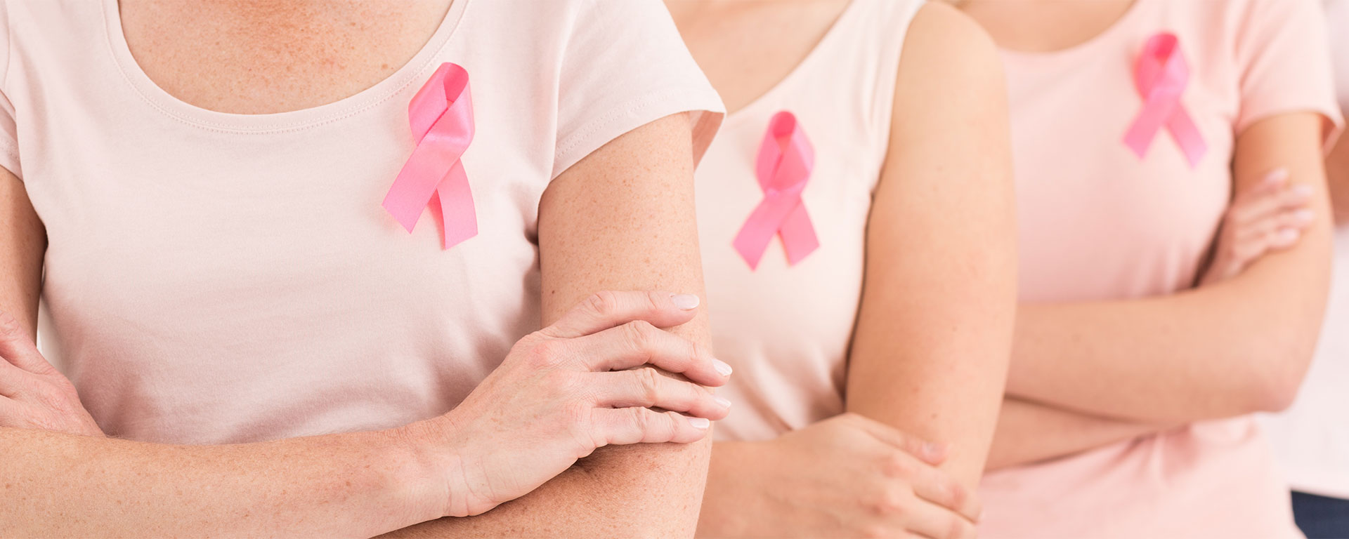 Zwei Frauen die eine rosa Schleife am T-Shirt tragen. Diese ist ein Symbol im Bewusstsein gegen Brustkrebs.
